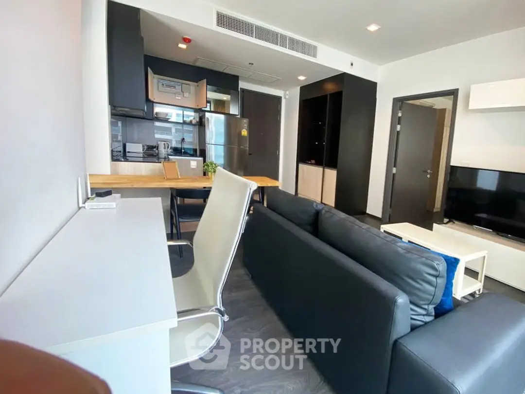Modern living room with sleek furniture and open kitchen layout in a stylish apartment.