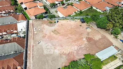 Aerial view of a vacant lot surrounded by residential houses with red roofs.