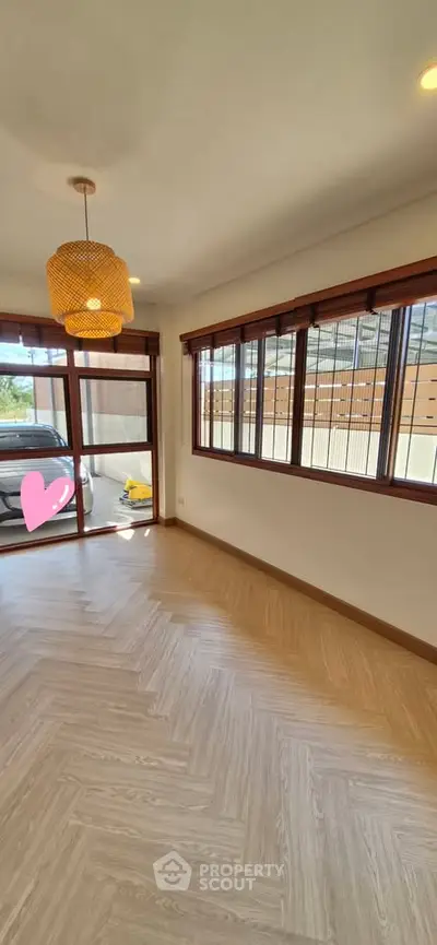 Spacious room with large windows and wooden flooring, ideal for natural light lovers.