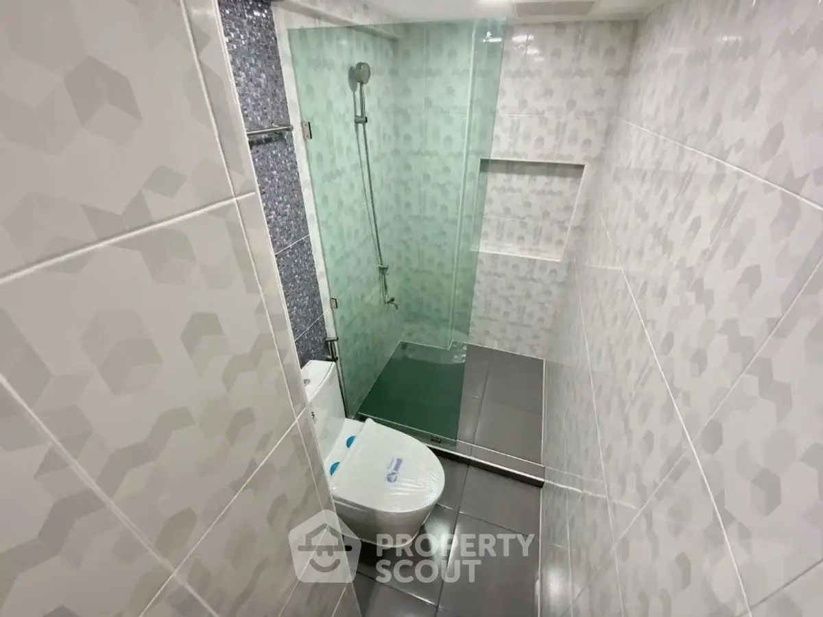 Modern bathroom with glass shower and geometric tile design