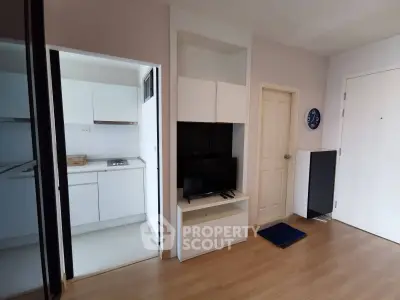 Modern apartment interior with sleek kitchen and cozy living area, featuring wood flooring and minimalist design.