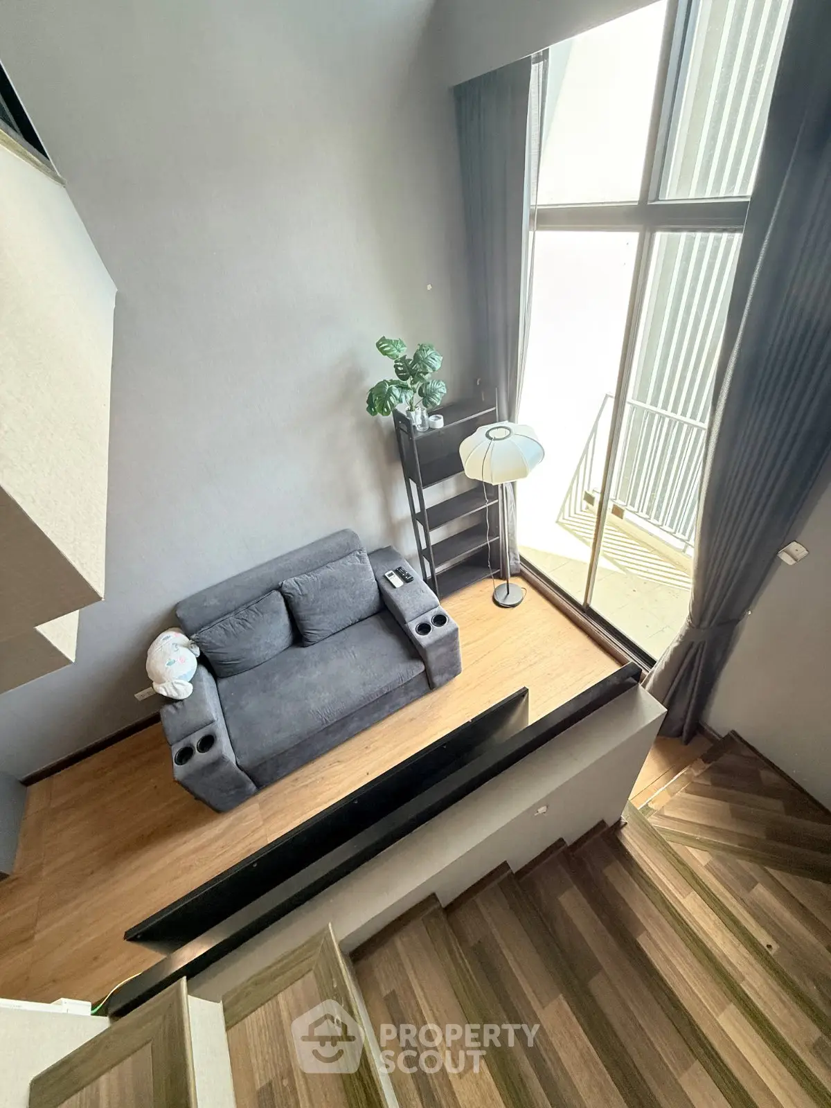 Modern loft apartment with high ceilings and large windows, featuring a cozy living area and stylish staircase.