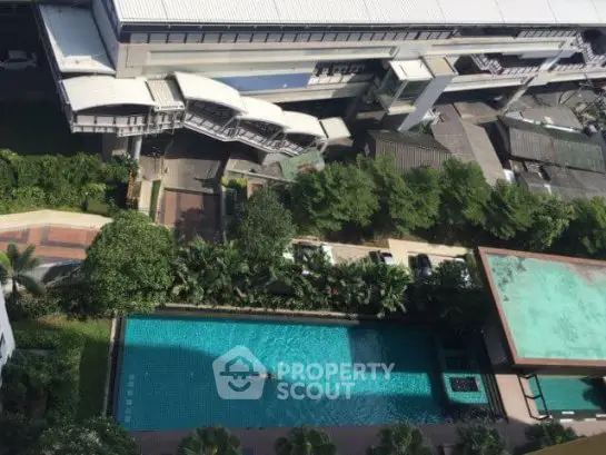 Aerial view of modern residential complex with swimming pool and lush greenery.