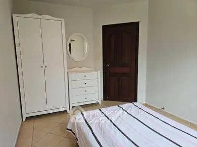 Cozy bedroom with white furniture and striped bedding, perfect for relaxation.