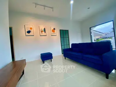 Modern living room with blue sofa and abstract art, bright and inviting space.