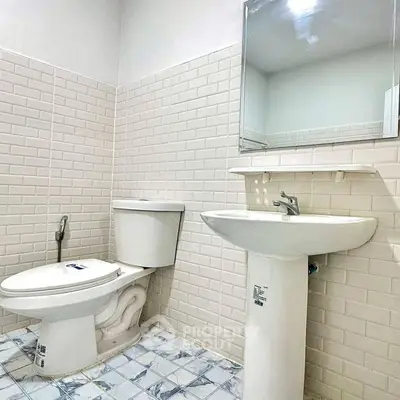 Modern bathroom with white tiles and pedestal sink, ideal for compact spaces.