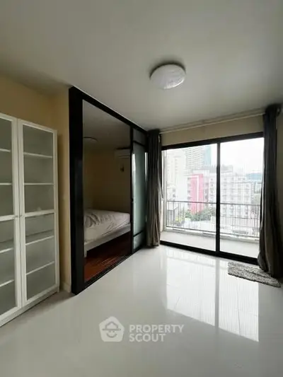 Modern apartment with glass-walled bedroom and city view balcony, featuring sleek white shelving.