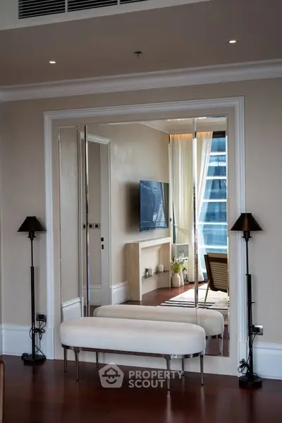 Elegant living room with modern decor and large mirror reflecting natural light.