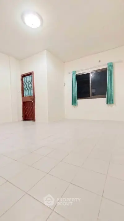 Spacious empty room with tiled floor and window, ideal for customization.