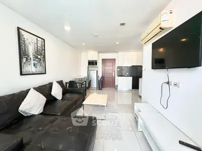 Modern living room with sleek black sofa, wall-mounted TV, and stylish kitchen area.