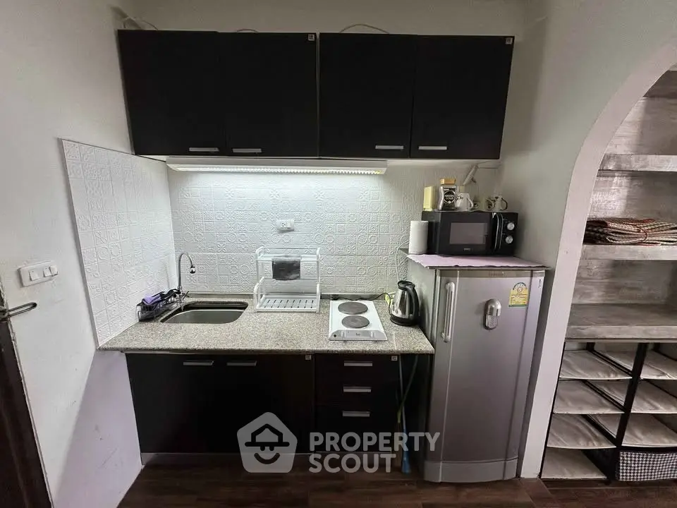 Compact kitchen with modern appliances and sleek cabinetry in a cozy apartment setting.