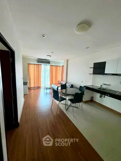 Spacious open-layout living room with modern kitchen and large windows in a stylish apartment.