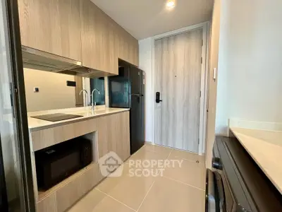 Modern compact kitchen with sleek appliances and wooden cabinetry in a stylish apartment.