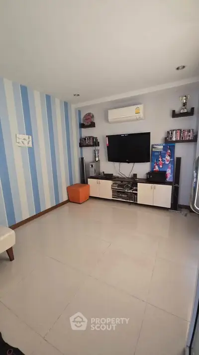 Modern living room with striped accent wall, wall-mounted TV, and sleek storage unit.