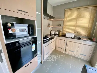 Modern kitchen with sleek appliances and wooden cabinetry, featuring a built-in oven and microwave.