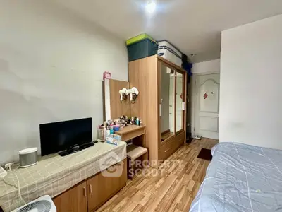 Cozy bedroom with wooden flooring, wardrobe, and TV setup for modern living.