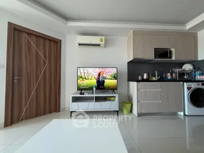 Modern living room with sleek kitchen, TV, and washing machine in stylish apartment.