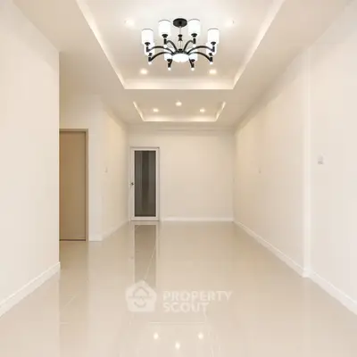 Spacious modern living room with elegant chandelier and glossy tile flooring.
