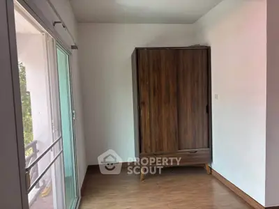 Minimalist room with wooden wardrobe and sliding glass door to balcony