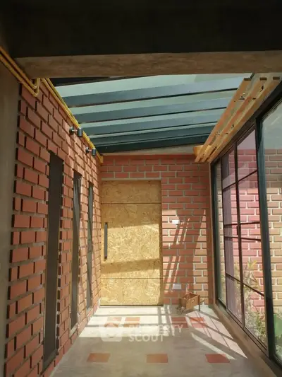 Charming sunlit corridor with brick walls and glass ceiling in modern home.