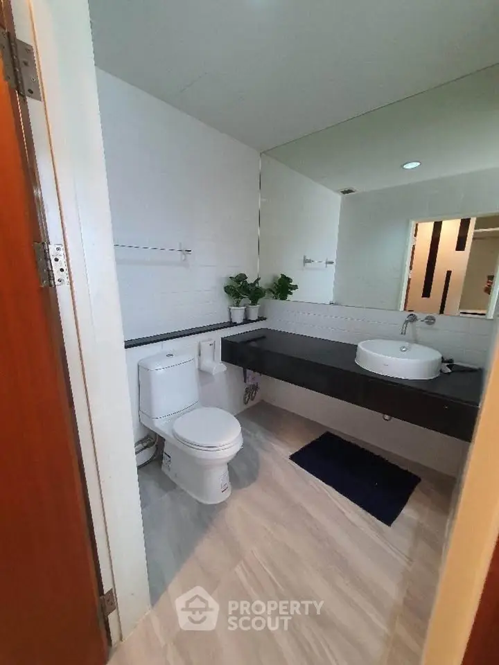 Modern bathroom with sleek design, featuring a white toilet, stylish sink, and elegant flooring.