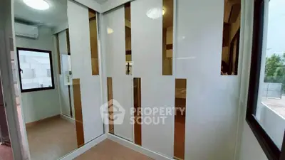 Modern bedroom with sleek mirrored wardrobes and large windows for natural light.
