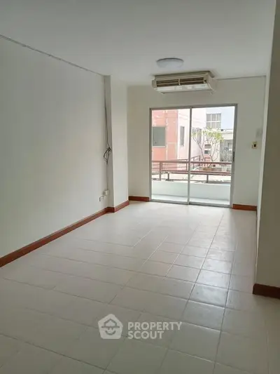 Spacious unfurnished room with large window and air conditioning, ideal for customization.