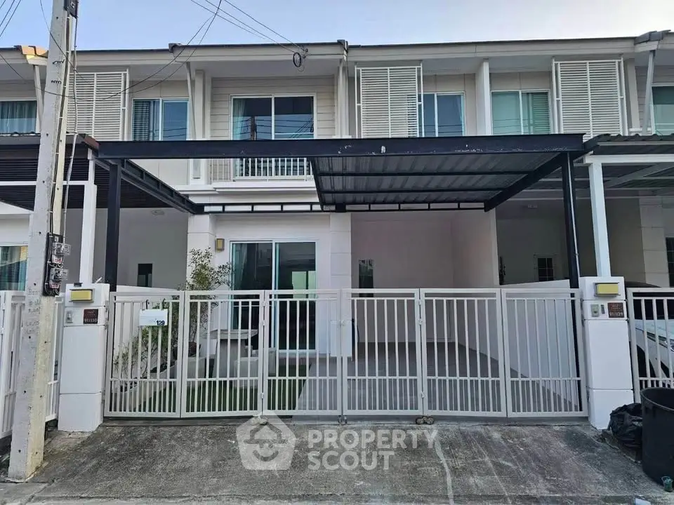 Modern townhouse exterior with gated driveway and covered parking area.