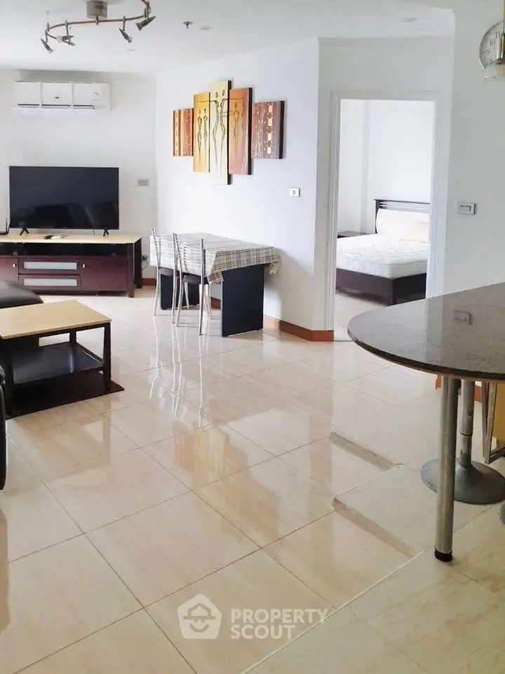 Spacious modern living room with open layout and stylish decor, featuring a glimpse into a cozy bedroom.