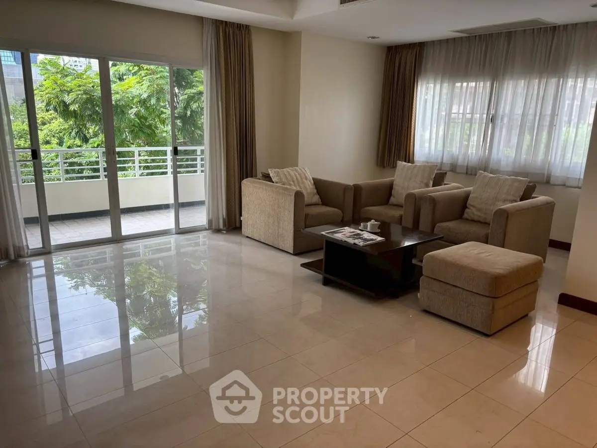 Spacious living room with modern furniture and large windows opening to a balcony.