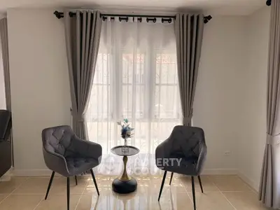 Elegant living room with stylish chairs and natural light through large window.
