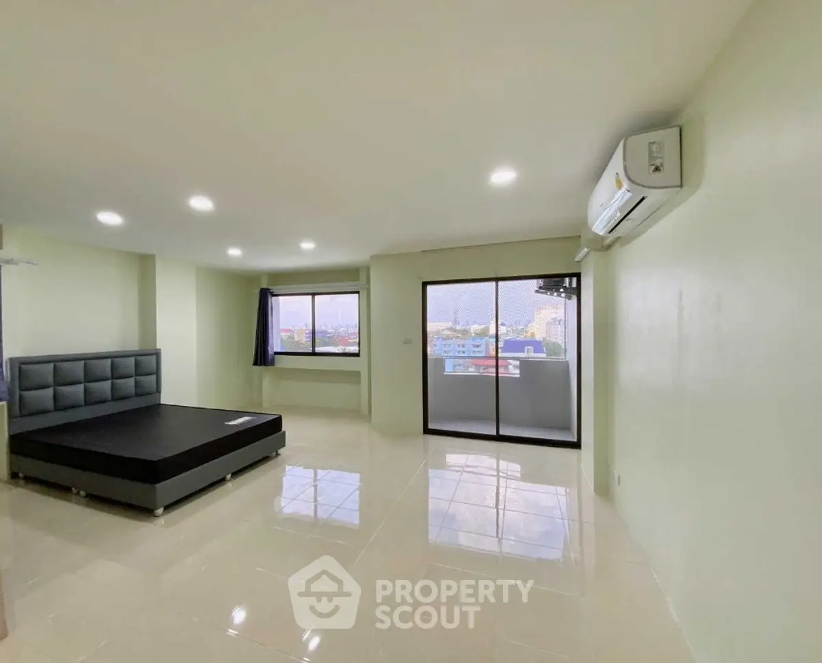 Spacious bedroom with modern design and city view balcony access.