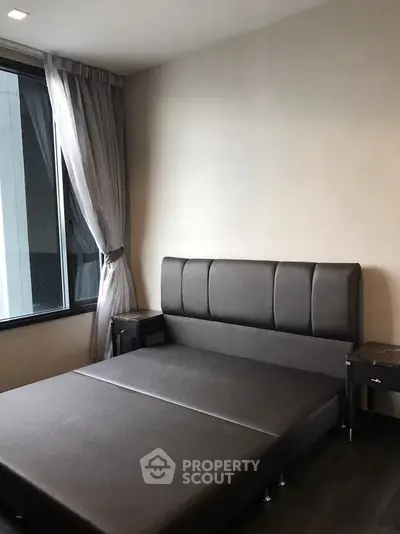 Modern bedroom with stylish bed and large window offering natural light.