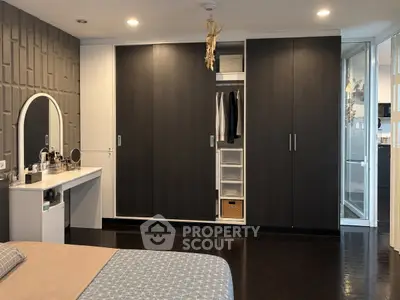Modern bedroom with sleek dark wood wardrobe and stylish vanity area, perfect for contemporary living.