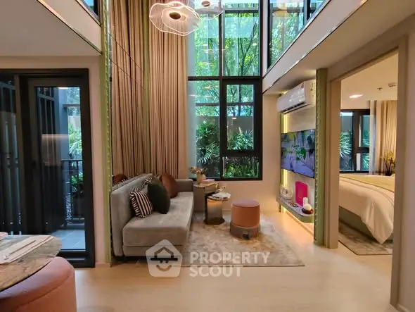 Modern living room with high ceilings and large windows, featuring stylish furniture and a view into a cozy bedroom.