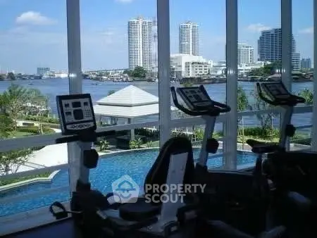 Luxurious gym with stunning river view and modern equipment in high-rise building.