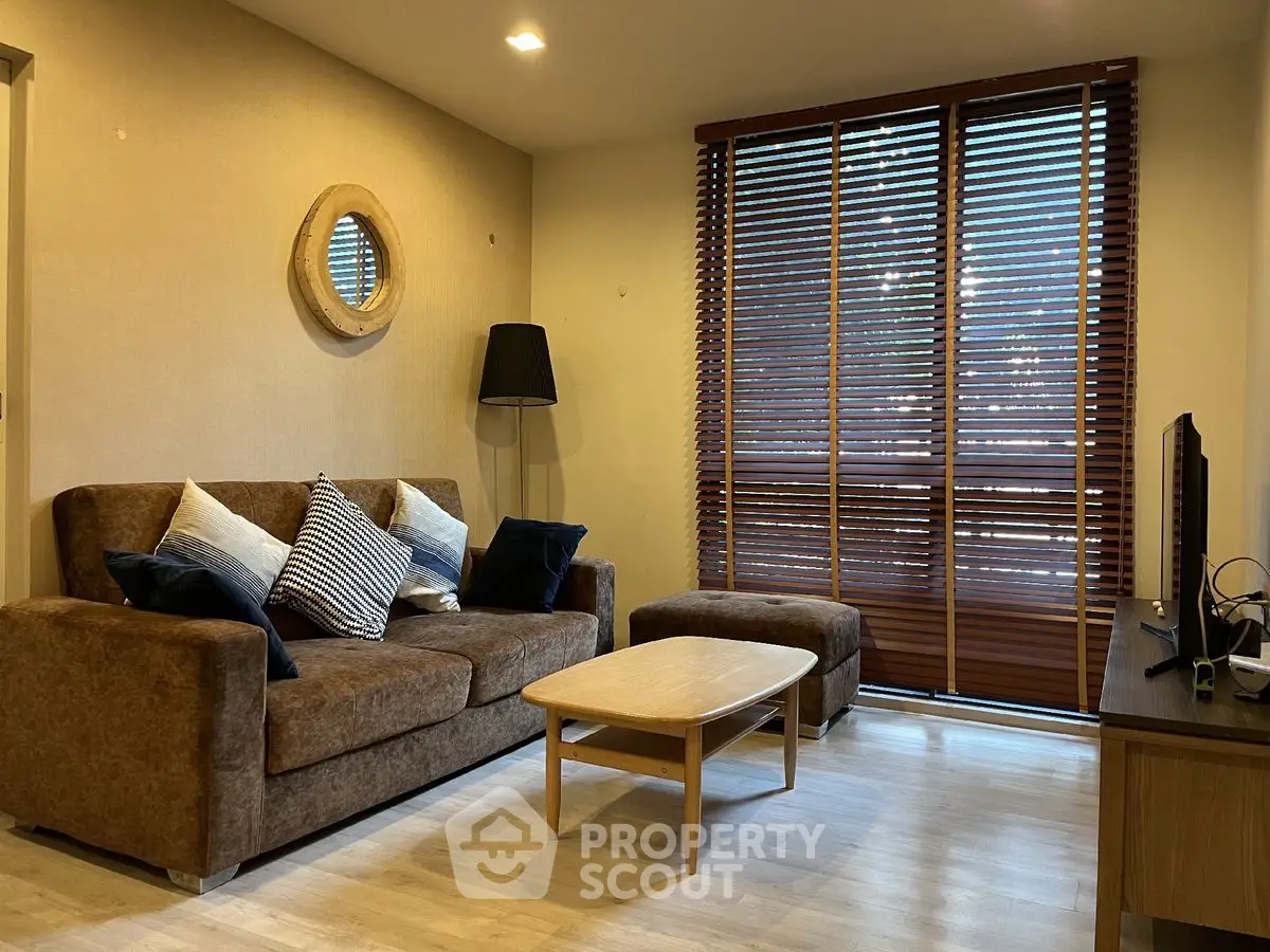 Cozy living room with brown sofa, wooden coffee table, and large window blinds.