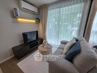 Cozy living room with modern decor, large window, and comfortable seating in a stylish apartment.