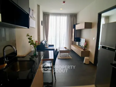 Modern living room with sleek kitchen, stylish furniture, and large window for natural light.