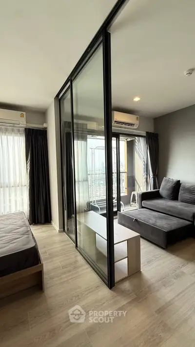 Modern apartment with glass partition, cozy living area, and balcony view.