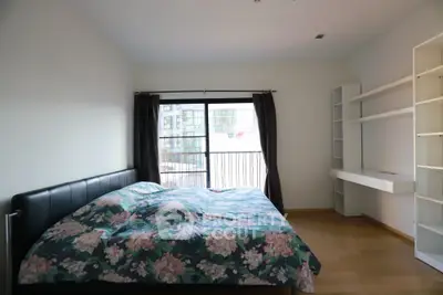 Spacious bedroom with modern decor and large window offering natural light.