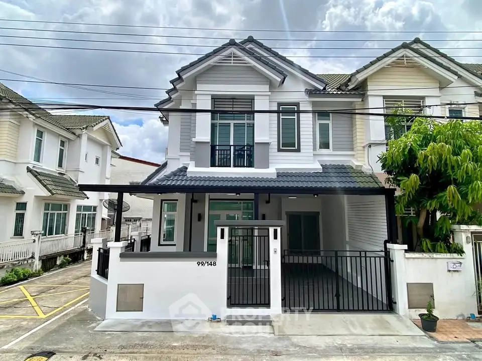 Charming two-story house with modern facade and gated driveway in a serene neighborhood.