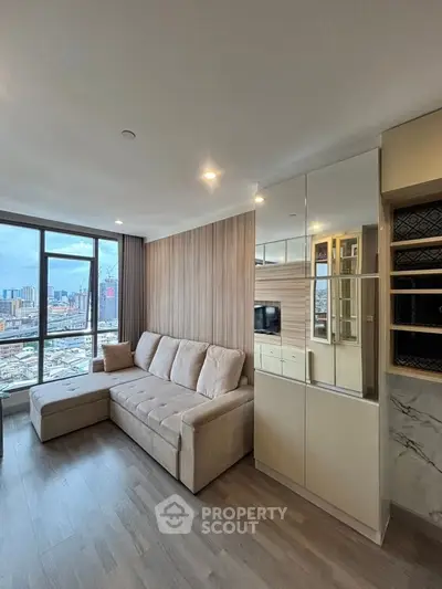 Modern living room with city view, featuring a cozy beige sofa and sleek storage cabinets.