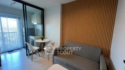 Modern living room with cozy sofa and dining area, featuring stylish wood paneling and natural light.