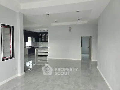 Spacious modern living room with open kitchen layout and sleek tile flooring.