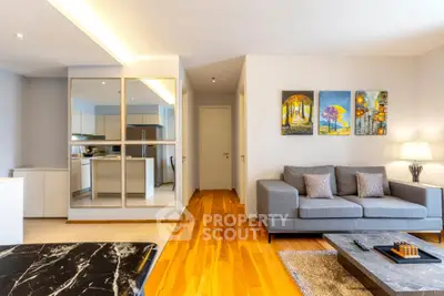 Modern living room with stylish decor and open kitchen layout, featuring hardwood floors and contemporary furniture.