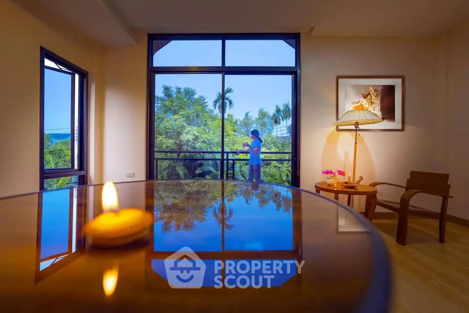 Spacious living room with large windows offering lush garden views and elegant decor.