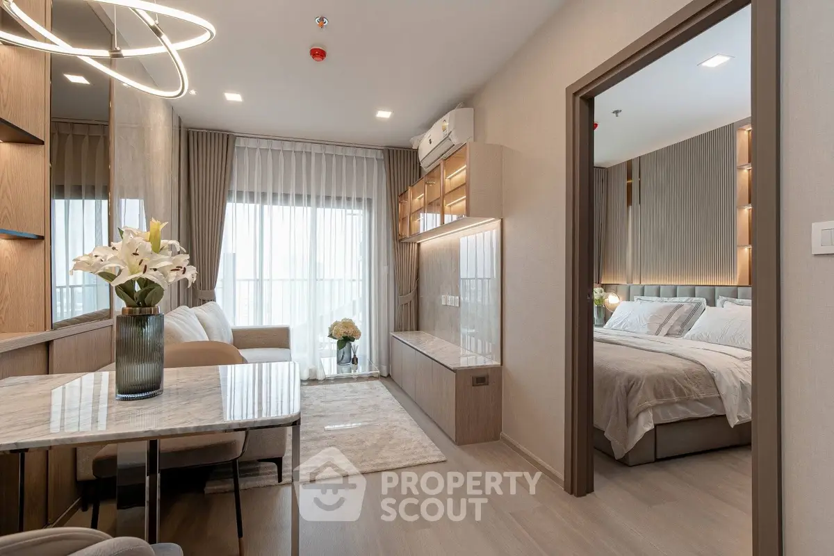 Modern open-plan living room with elegant decor and adjacent cozy bedroom in a stylish apartment.