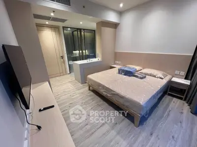 Modern bedroom with sleek design and en-suite bathroom, featuring a wall-mounted TV and stylish flooring.