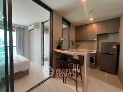 Modern open-layout kitchen with breakfast bar and adjacent bedroom in stylish apartment.